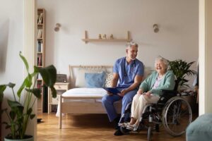 A middle-aged person holds the hand of an elderly relative in a warm, softly lit living room.