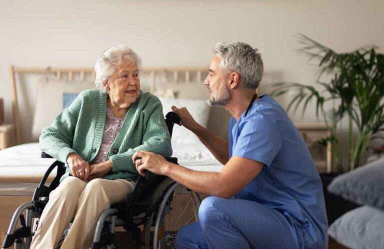 Older adults practice supported walking exercises in a bright assisted living activity room.